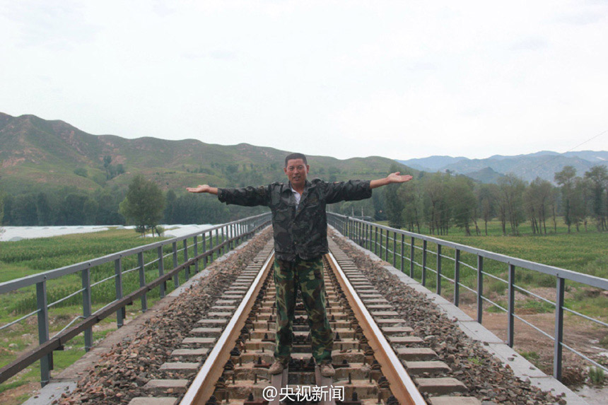 صورة: يعيد لو وي صورة إشارته لإيقاف القطار وهو واقف في منتصف المسارات.