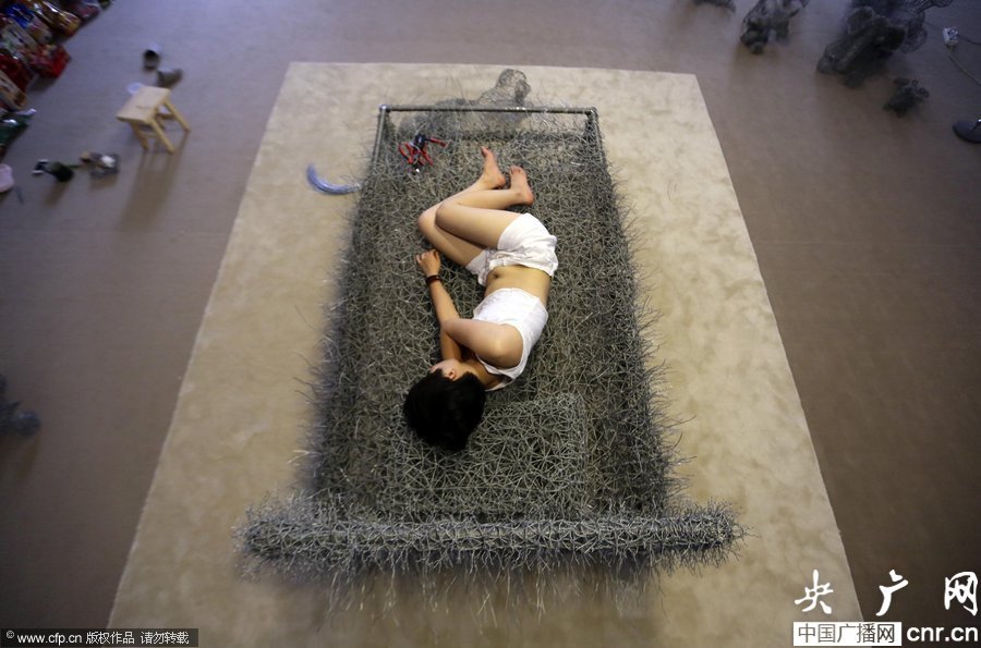 مذهل... فنانة صينية تنام "عارية"على سرير الأسلاك