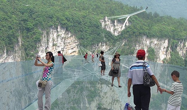 يظهر في الصورة التصميمية زوار يلعبون على أطول الجسر الزجاجي الشفاف