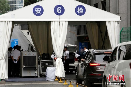 يظهر في الصورة العمال يقومون بفحص جذع السيارات في شارع وانغ فو جينغ قبل دخولها إلى الفنادق والمتاجر.    