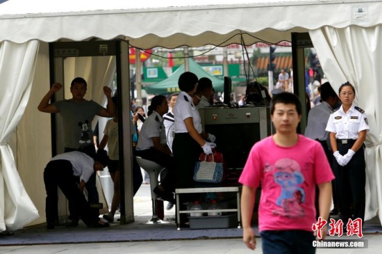 يظهر في الصورة العمال وهم يقومون بالفحص الأمني للأشخاص وطرودهم في مركز تسوق بشارع وانغفوجينغ.   