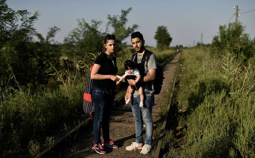 يعبر لاجئ عراقي أحمد مع وزجته وطفلهما يبلغ عمره 4 سنوات الحدود بين مقدونيا وصربيا
