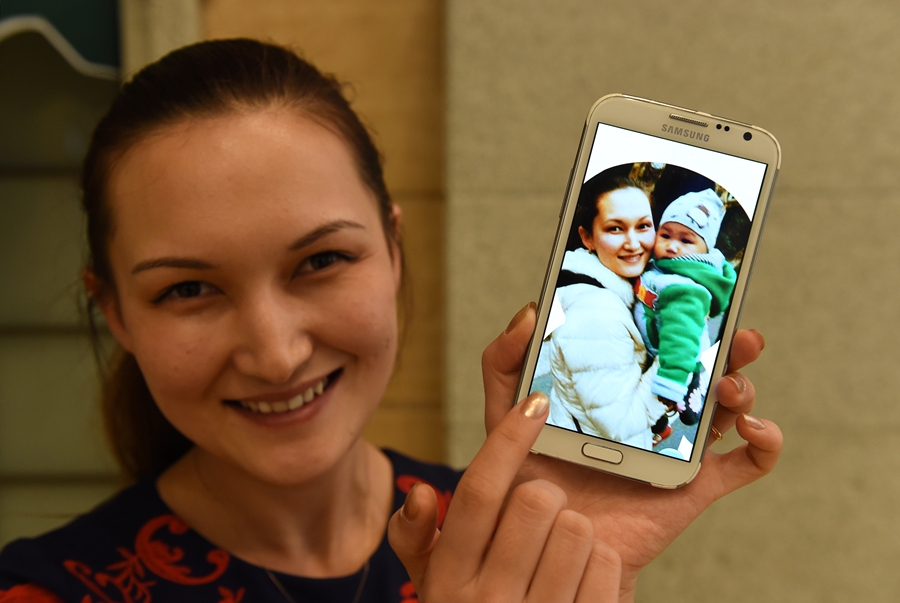 آيي بوشاكه تعرض على هاتفها صورة مع طفلتها بيقهمايي بعد نجاح جراحة قلب خضعت لها في 15 نوفمبر 2014