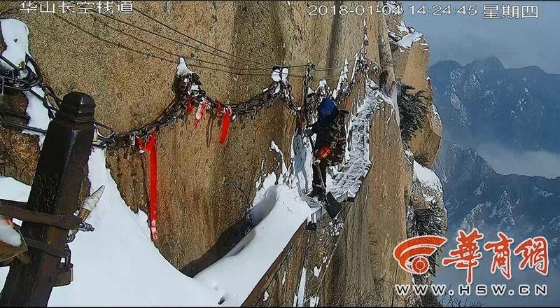 عمال تنظيف الثلج على درب خشبي معلق على جبل هواشان
