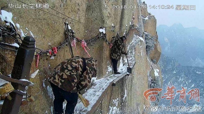 عمال تنظيف الثلج على درب خشبي معلق على جبل هواشان