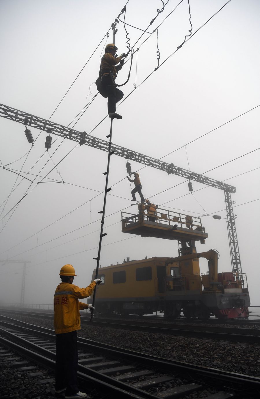 عمال يجرون أعمال الإصلاح على خط السكة الحديدية في جنوبي الصين
