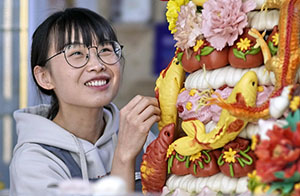 فتاة شابة تروج لفن صناعة معجنات الهوامو التقليدية في بكين