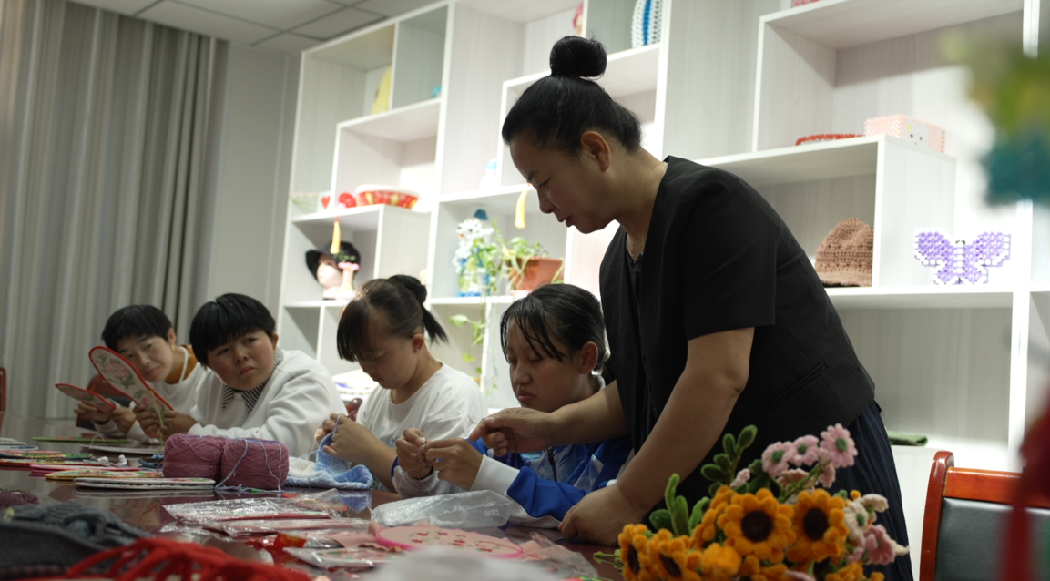 شو هاي شيا تتفقّد أعمال النسيج اليدوي في مركز خدمات ذوي الإعاقة.